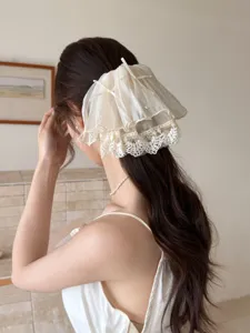 Detailed view of an elegant beige lace bow hair claw clip styled on a low ponytail