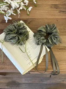 Detailweergave van donkergroene organza scrunchies met lange linten op een oud boek.