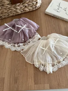 Close-up detail of romantic French bow lace skirt hair claw clips on a wooden surface