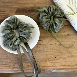 Elegante groene organza haarelastiekjes met lange linten op een rustieke houten tafel