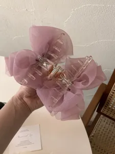 Gros plan d'une élégante pince à cheveux avec nœud en tulle rose et perles à la main
