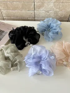 Gros plan de chouchous en résille colorée avec nœuds et perles sur une surface blanche.