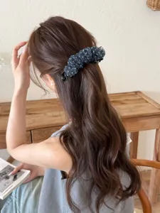 Vue détaillée d'une pince à cheveux banane élégante en résille à pois bleu marine.