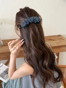 Détail de la pince banane en mousseline à pois marine sur cheveux châtains