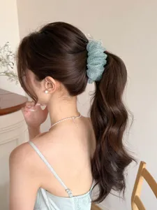 Détail d'une pince à cheveux banane en maille à pois vert clair sur une queue de cheval