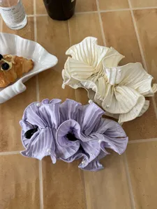 Detail of elegant satin banana clips with pleated ruffles and decorative pearls.