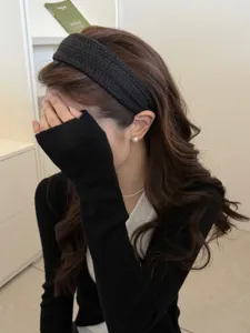 Close-up of a stylish wide black knitted headband creating a high cranial top look