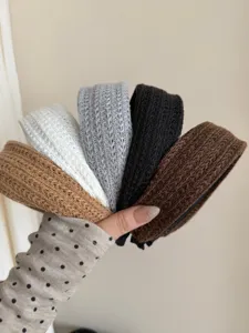 Macro detail of wide knitted headbands showing multi-color textured weave patterns
