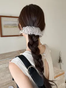 Vue rapprochée d'une pince à cheveux à pois dans une natte brune tressée élégante.