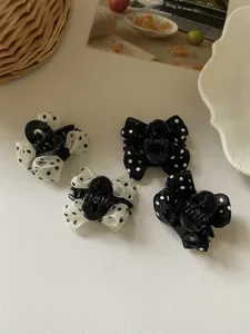 Dettaglio di quattro mini mollette per capelli a pois con fiocco dolce in bianco e nero