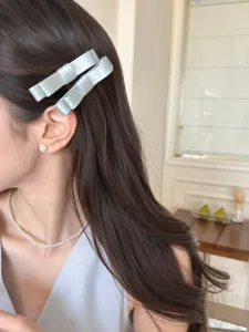 Detailansicht von eleganten hellblauen Satin-Schleifen-Haarspangen im Frauenhaar
