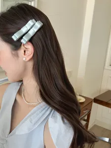 Seitenansicht eines Models mit eleganten hellblauen Satinschleifen-Haarspangen