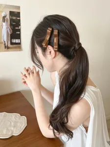 Detailansicht von eleganten braunen Satin-Haarspangen mit Schleife am Seitenzopf