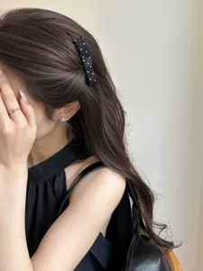 Close-up detail of a sweet black polka dot bow hair comb worn on a side hair style