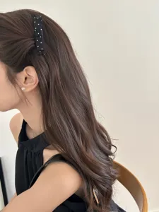 Close-up detail showing a sweet black polka dot bow hair clip on long wavy brown hair