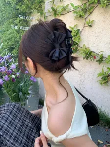 Rear view of an elegant black satin bow hair claw clip on a woman's updo.