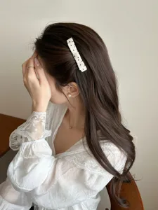 Close-up view of a sweet white polka dot bow hair clip worn on long brunette wavy hair