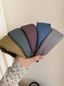 Detail view of five assorted solid-colored wide cloth headbands held in a hand