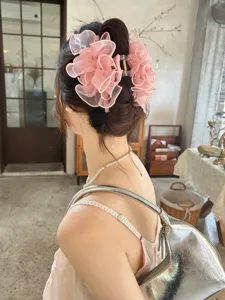Detailweergave van een grote roze haarklem met mesh strik gedragen op een lage knot