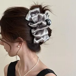 Side view detail of an elegant silver ribbon hair claw clip used in a stylish updo