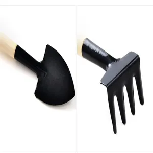 Mini garden tool detail shot featuring shovel and rake with wooden handle and black head.