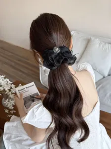 Vue détaillée de l'élastique à cheveux noir en organza sur une queue de cheval