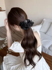 Détail d'un chouchou géant en résille noire avec perle de cristal sur cheveux ondulés
