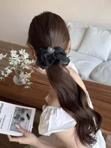 Chouchou élégant en organza noir avec cristal sur de longs cheveux ondulés bruns