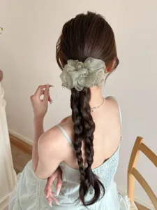 Vue détaillée d'un chouchou en mesh organza vert sauge sur une coiffure tressée élégante