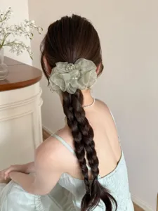 Vue arrière détaillée d'un chouchou en organza vert clair sur une longue tresse