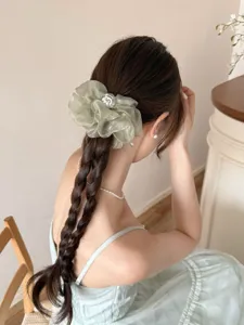 Détail d'un chouchou en organza vert sauge porté sur les cheveux tressés d'un modèle