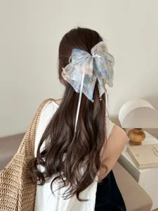 Detailed view of an oversized blurred mesh floral bow hair clip on long wavy hair