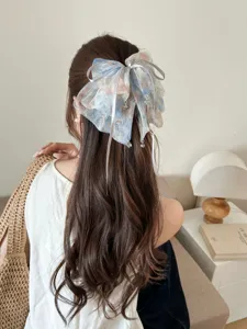 Close-up of large blue floral mesh bow hair claw on long wavy brown hair