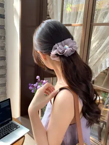 Elegante pinza de plátano con lazo plisado morado mostrada en una coleta con estilo