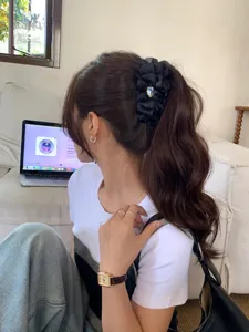 Primer plano de una pinza de plátano negra rizada con corazón de cristal en el pelo