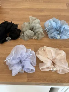 Vue de dessus de cinq chouchous en maille colorée : noir, vert, bleu, violet et pêche.