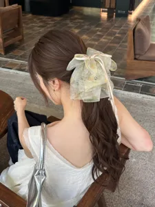 Detailed view of an elegant fairy style dyed mesh bow hair clip on long wavy hair.