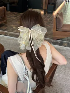 Back view detail of a large dyed mesh bow hair clip on elegant brown wavy hair