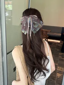 Close-up detail of a romantic dyed mesh bow hair clip accessory on long wavy hair