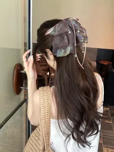 Close-up of a blurred mesh bow hair claw clip styled on long wavy brown hair