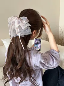 Back view of a layered mesh fairy bow hair clip on long wavy brown hair.