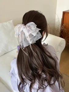 Detail view of large ethereal gauze bow hair clip with ink-wash floral patterns on hair
