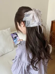 Back view of woman wearing large purple mesh bow hair clip in a home setting