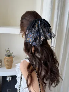 Detail view of a French style floral mesh bow hair clip worn on long wavy brown hair.