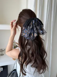 Close-up detail of a French style floral mesh bow hair clip worn on long wavy brown hair