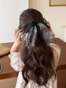 Detail view of a French elegant floral mesh bow hair clip on a woman's ponytail.
