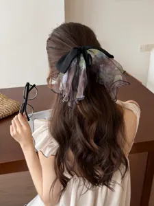 Back view of a woman wearing an elegant French floral mesh bow hair clip in wavy hair.