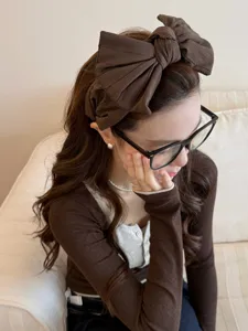 Gros plan détaillé du large bandeau à nœud marron plissé porté sur de longs cheveux