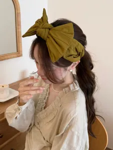 Vue rapprochée détaillée d'un élégant serre-tête à gros nœud vert olive sur un mannequin