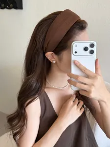 Primer plano de una diadema ancha de tela marrón usada por una modelo para un look elegante y chic